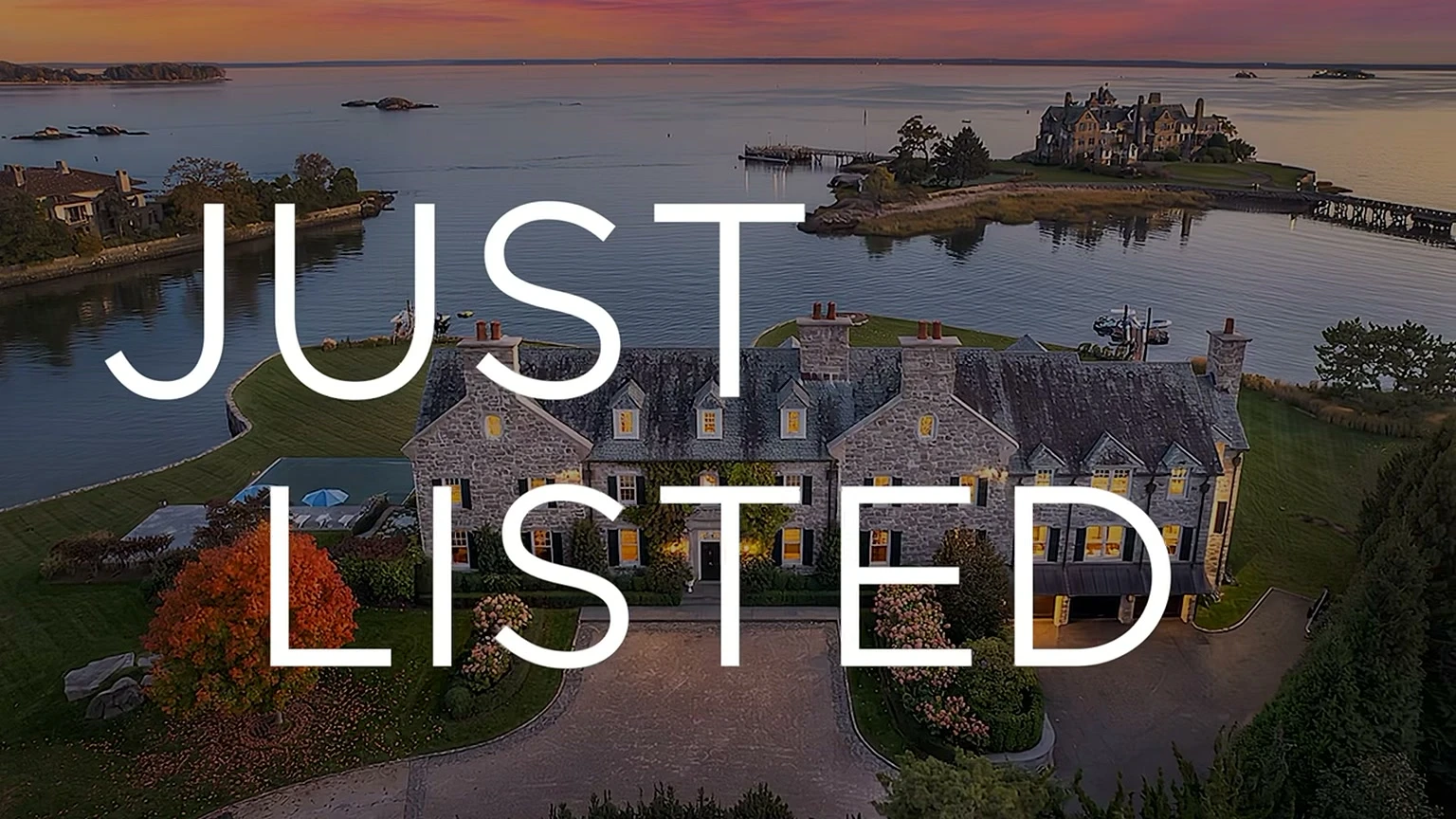Aerial view at sunset of a waterfront stone estate, with a Just Listed title card over it